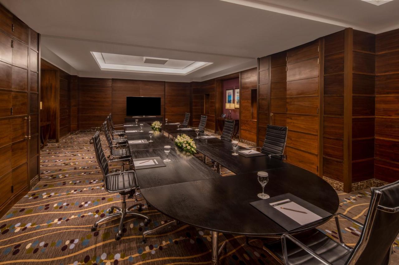 Makkah Clock Royal Tower, A Fairmont Hotel Mekka Eksteriør bilde The photo depicts a modern conference room designed for meetings and presentations. It features a large, oval table surrounded by ergonomic chairs. The room has a warm, wooden paneling on the walls and a textured carpet with various patterns. A telev